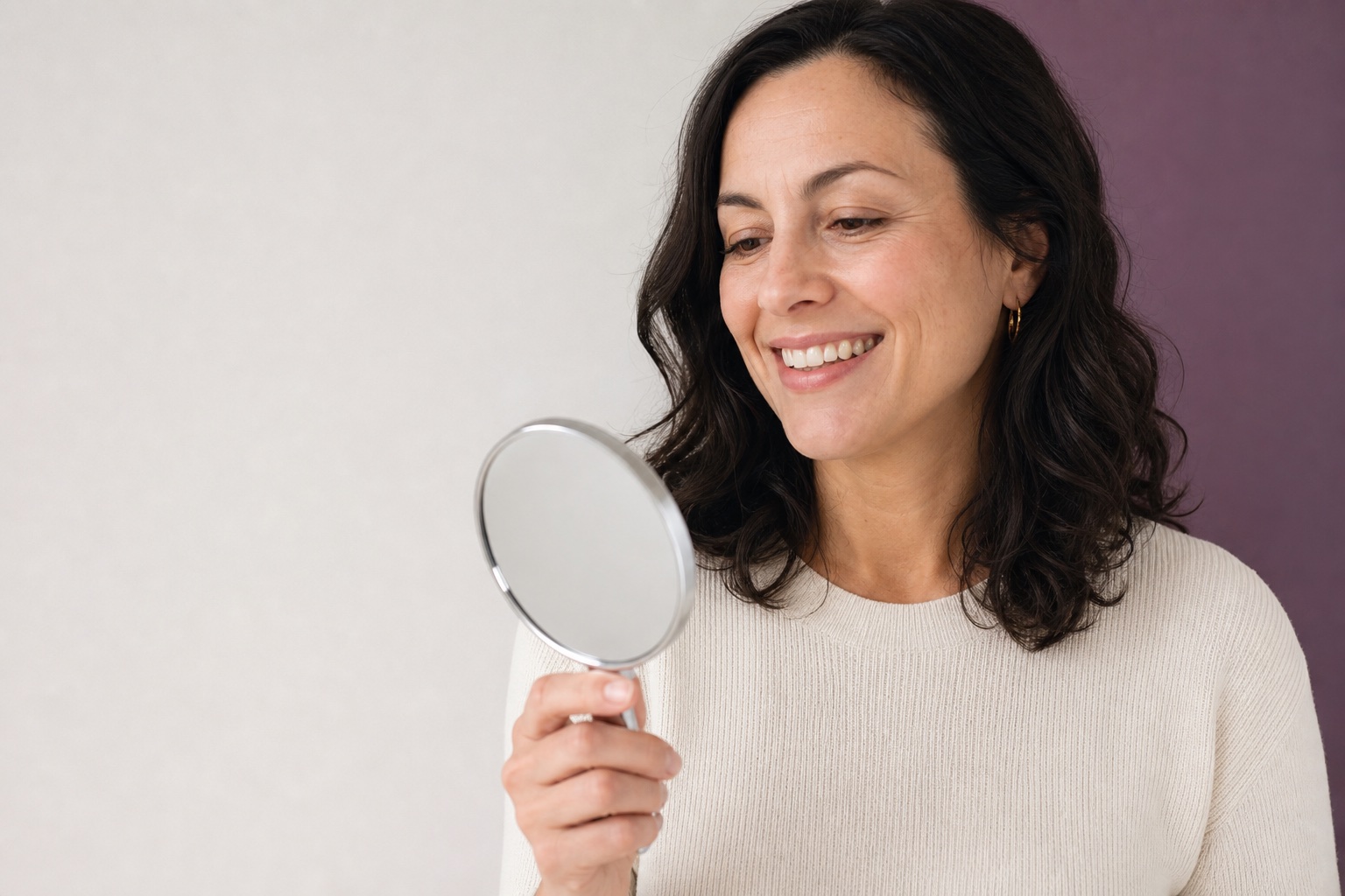 Adult looking at their smile in a hand mirror